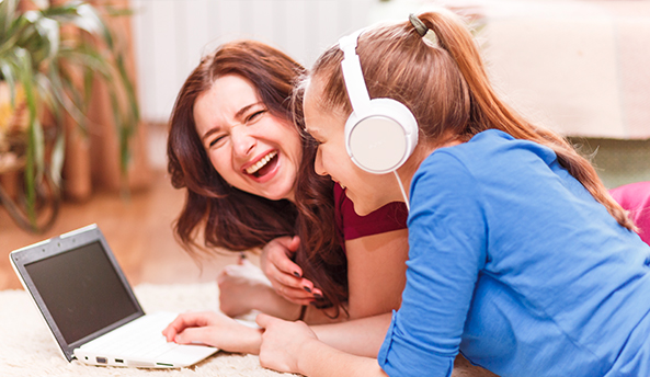 Two young women enjoying an activity on a laptop together outdoors.