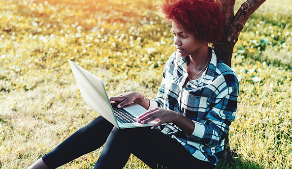 A young woman in deep focus on her laptop outdoors