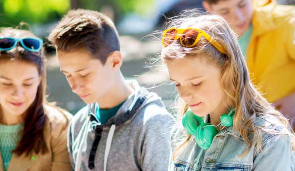 Group of three students enjoying their digital devices outdoors.