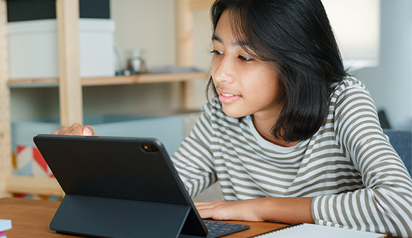 Young girl smiling at what she is watching on her iPad.