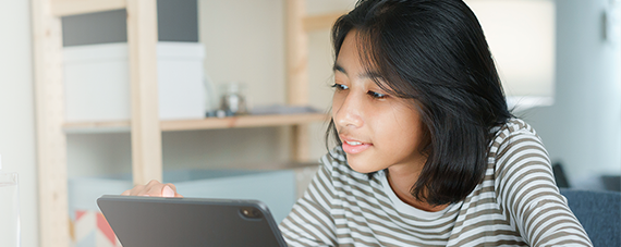 Young girl smiling at what she is watching on her iPad.