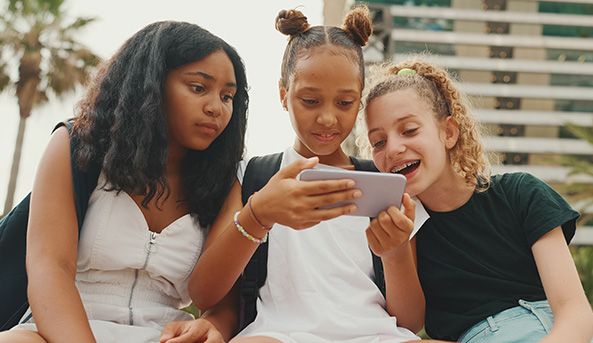 Young girls smiling at what they are watching on a mobile phone