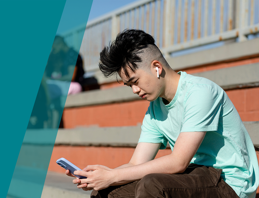 Teen boy using smartphone alone away from friends